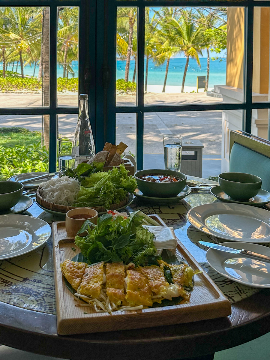 Vietnamese bánh xèo pancake with fresh herbs and rice noodles, ocean view through the window at Tempus Fugit, JW Marriott Phu Quoc