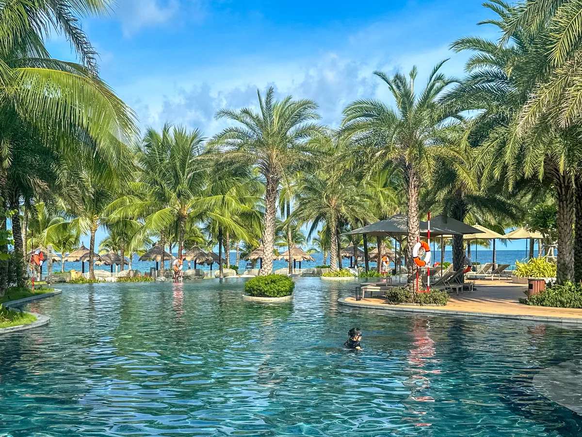 Resort pool with palm trees, loungers, and a wooden pergola photo spot at Crowne Plaza Phu Quoc