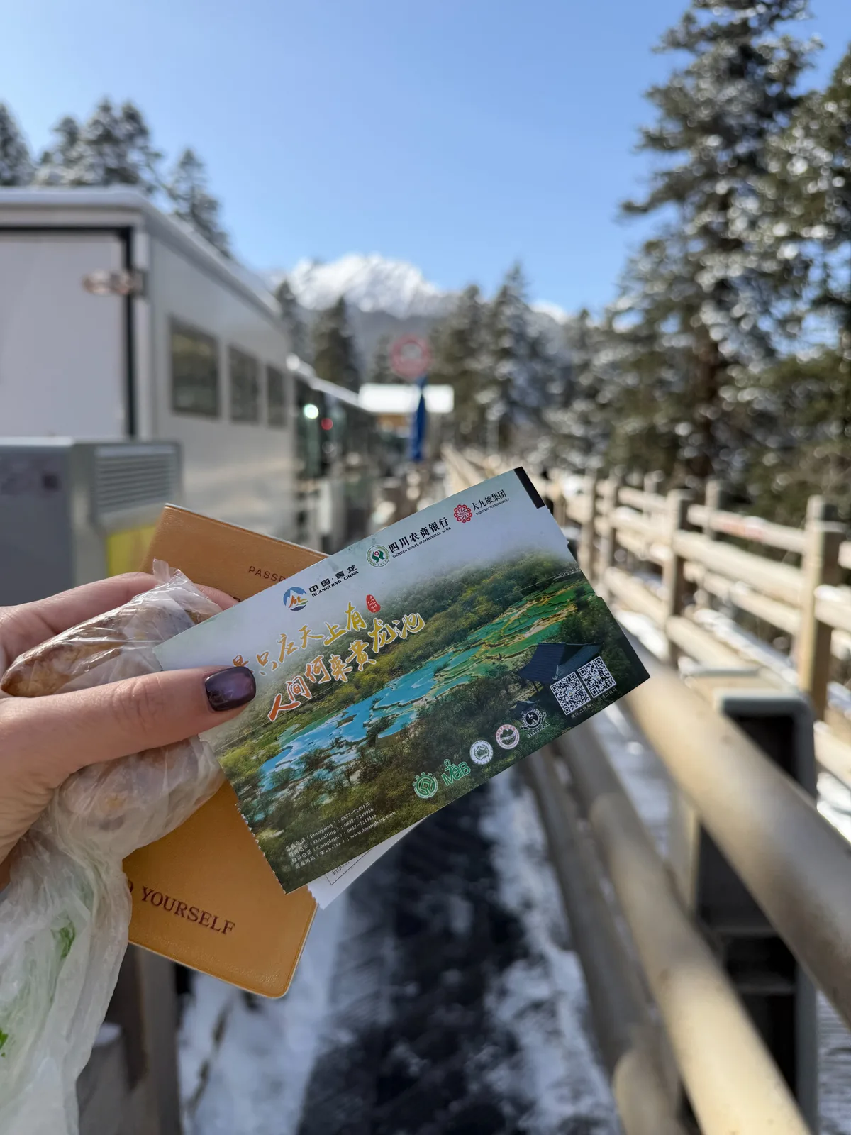 Holding a pre-booked Huanglong entrance ticket and passport near the cable car station