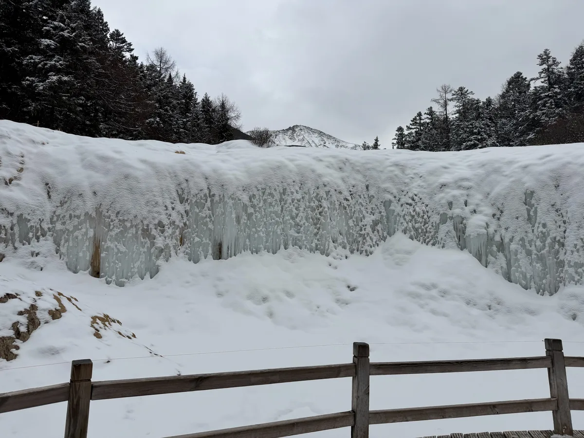 A waterfall frozen solid mid-flow on the Huanglong descent trail in winter