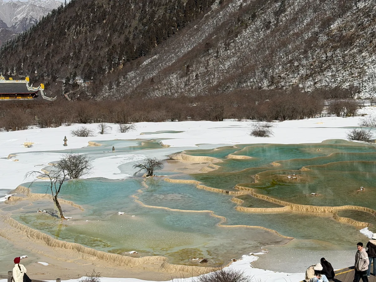 Terraced turquoise pools at Wuchi Pond with a traditional pavilion in the background