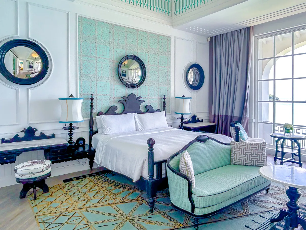 King bed with teal patterned headboard and round mirrors in the Turquoise Suite at JW Marriott Phu Quoc