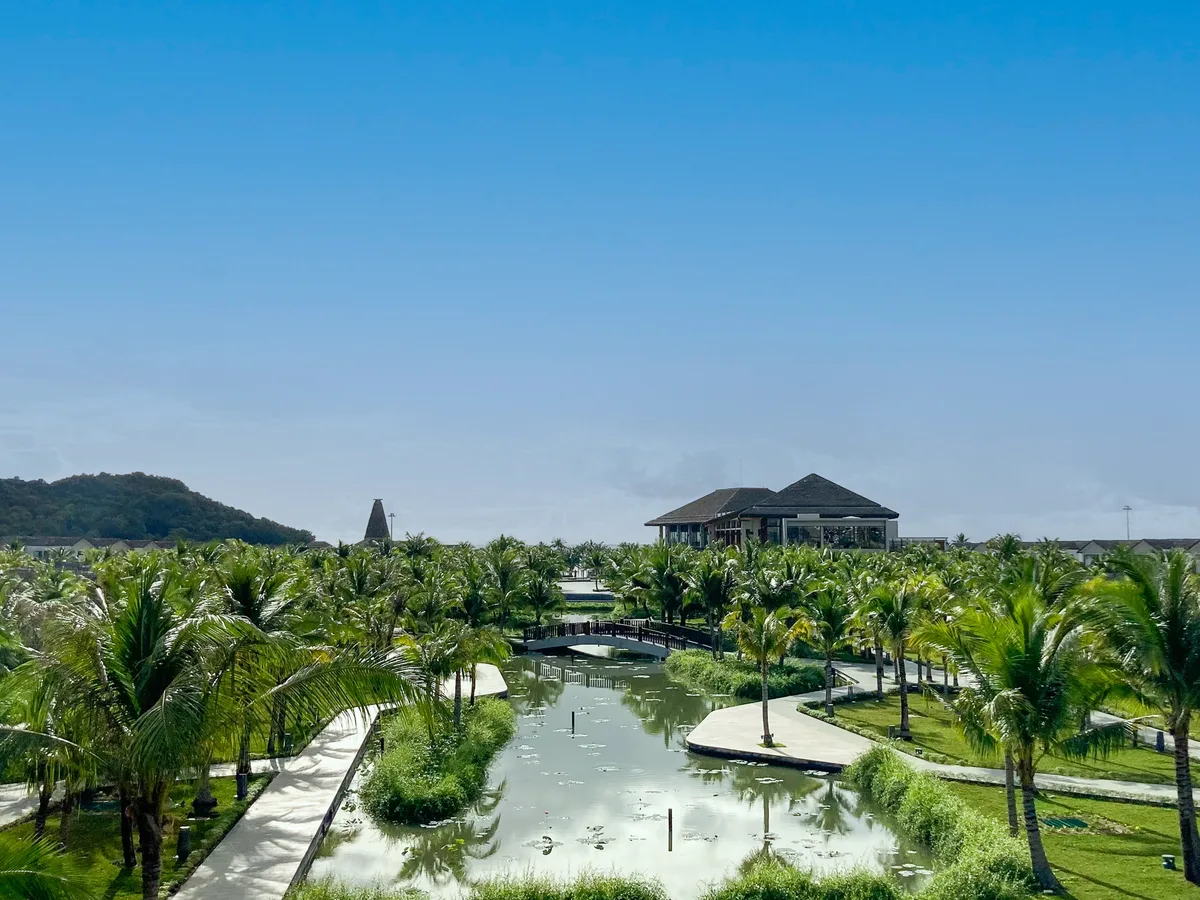 Aerial view of a lagoon, walking bridge and palm-lined grounds at New World Phu Quoc Resort