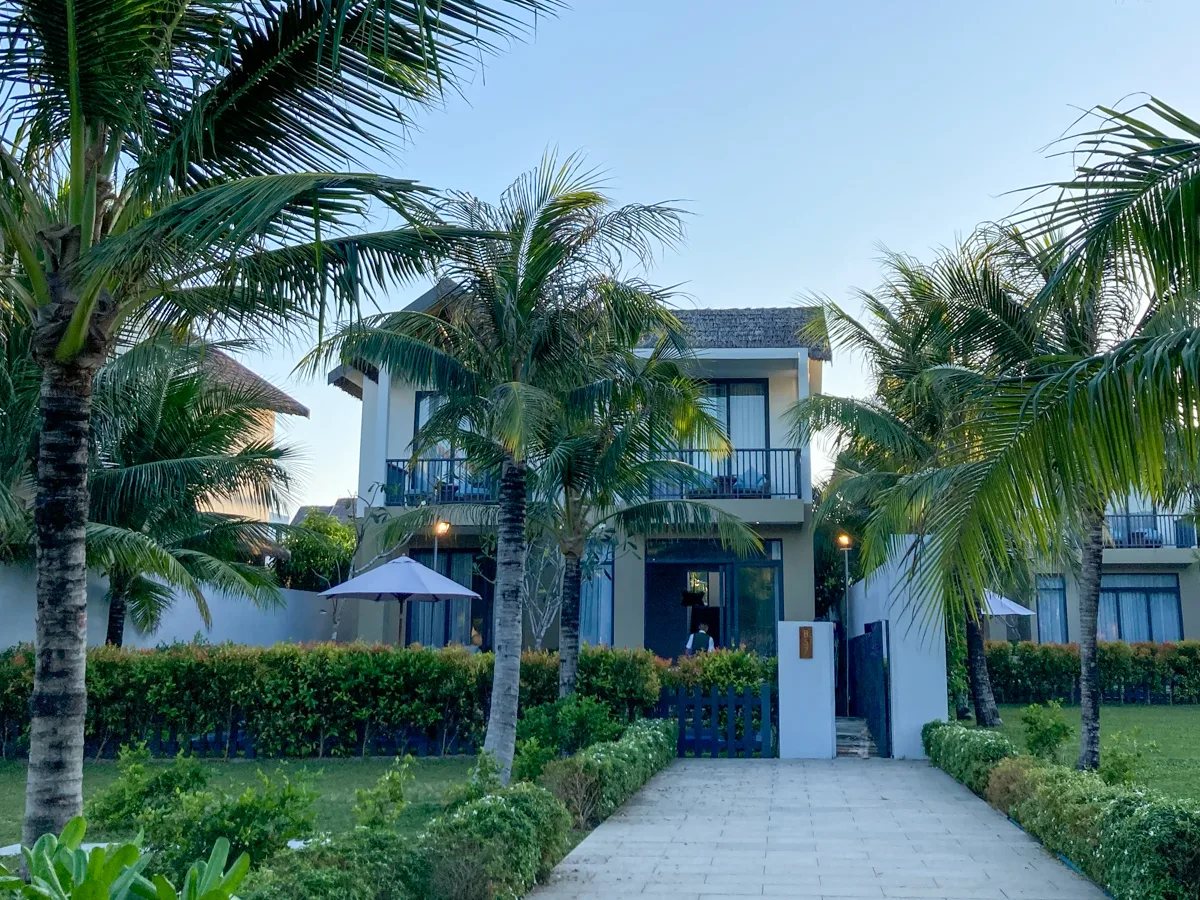 Two-story pool villa exterior with palm trees at New World Phu Quoc Resort