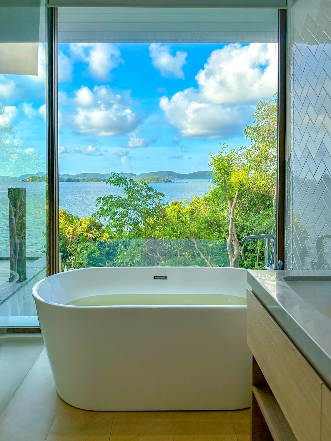 Freestanding bathtub facing a floor-to-ceiling ocean-view window at Premier Village Phu Quoc