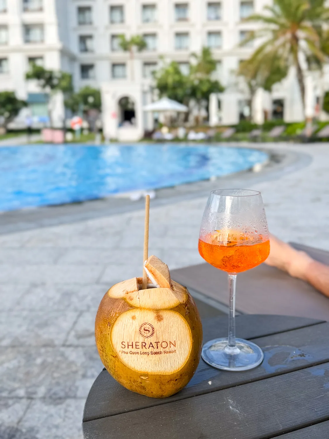 Branded coconut and Aperol spritz on a poolside table at Sheraton Phu Quoc