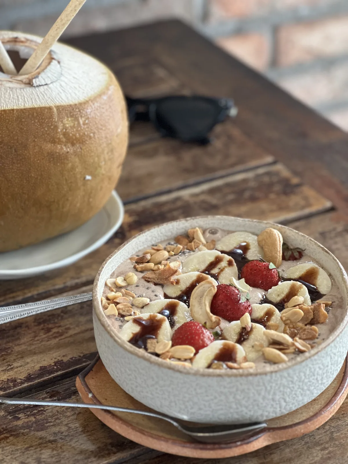 An acai bowl and fresh coconut at an oceanview cafe table in Phu Quoc