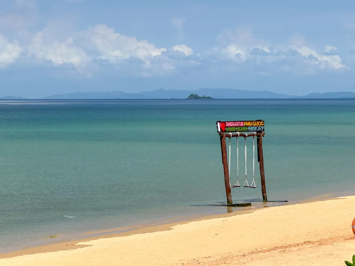 Windswept Phu Quoc beach with a swing set standing in the shallows near Long Beach